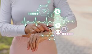 Image showing a woman's torso and arms; she is wearing a wearable device (smart watch) that monitors her vitals. Such wearables can be connected with AI.